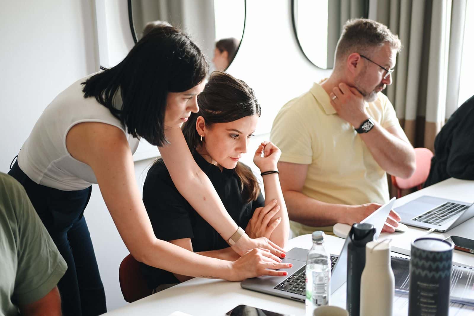 Three participants look at a laptop screen together