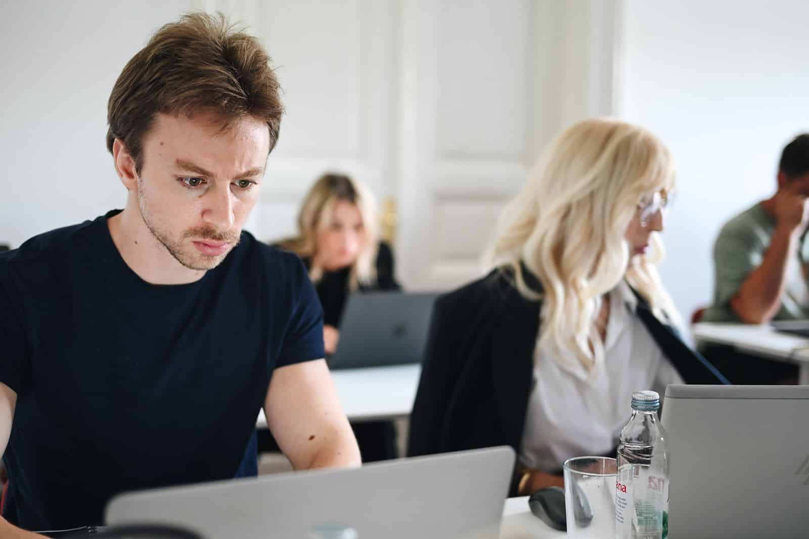 A participant works at a laptop, focused, in the bright hall