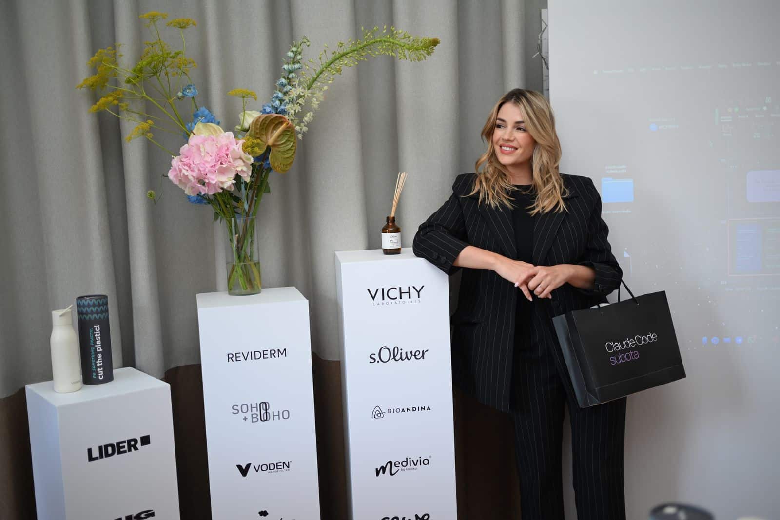 Astrid Čada by the partner plinths, holding a gift bag