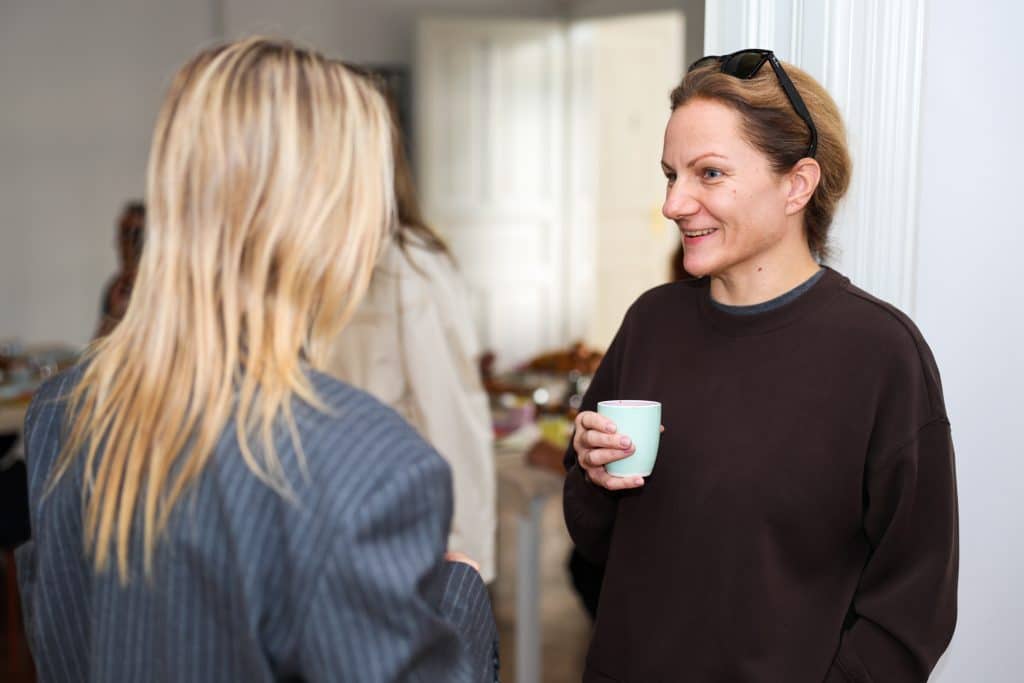 Two participants talking over coffee before Claude Code Saturday begins